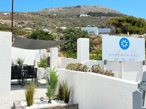 a white fence with a table and a sign at aeolian blu 10 in Parikia