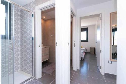 une salle de bain avec une douche à l'italienne et une porte vitrée dans l'établissement Apartamento costero en una comunidad de lujo, à Arenales del Sol