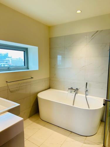 a white bath tub in a bathroom with a window at The Signature Suites at Cinnamon life Apartment in Colombo