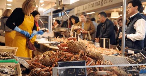 un groupe de personnes debout autour d'un marché de fruits de mer dans l'établissement Duplex marché de Talensac au cœur de Nantes, à Nantes