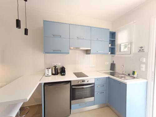 a white kitchen with blue cabinets and a sink at Panorama View in Agios Stefanos