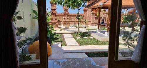 a view of a garden from a window of a building at Peaceful 2BR House with Rice Field View Near Beach & Local Spots in Mendaya