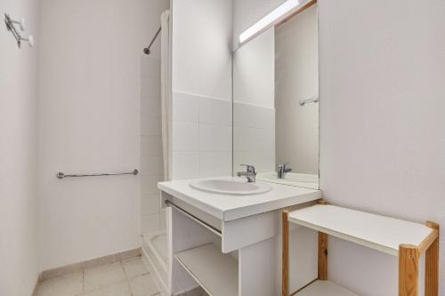 Un baño blanco con lavabo y espejo. en Résidence Odalys Le Grand Bleu, en Vendres-Plage