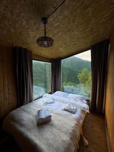 a bed in a room with a large window at Cottages in Chirdili in Chirdili