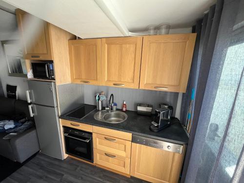 Elle comprend une petite cuisine avec des placards en bois et un évier. dans l'établissement Port nature 2 coursives sud, au Cap d'Agde
