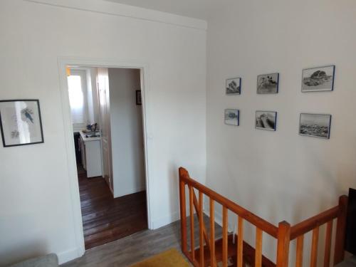 un couloir avec un escalier avec des photos sur le mur dans l'établissement Duplex charmant et calme avec vue sur Morlaix, à Morlaix