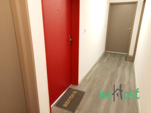 Cette chambre dispose d'une porte rouge et d'un couloir. dans l'établissement Flora - Studio Proche gare Parking, à La Rochelle