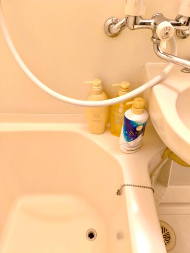 a bathroom with a sink and a bath tub with bottles on it at 鹿鸣新荣 in Nagoya
