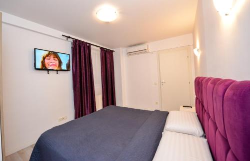 a bedroom with a bed and a tv on the wall at Royal Accommodation in Bucharest