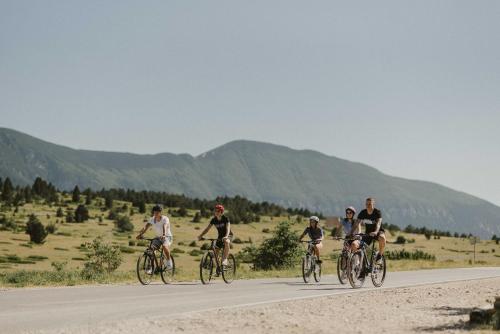 a group of people riding bikes down a road at Pinelle Blidinje A-Frame House in Risovac