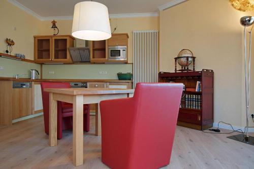 a kitchen with a table and a red chair at Ferienhaus Seegang Mit Eingezäuntem Grundstück in Flessenow