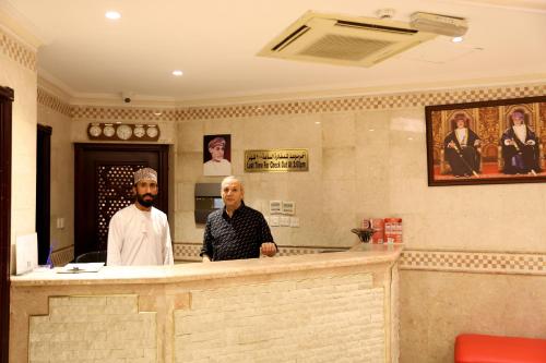 two men standing at a bar in a restaurant at Bayan International Hotel in Mawāliḩ