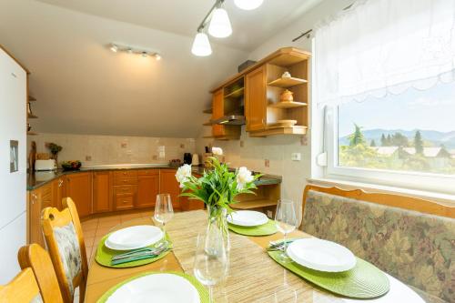 a dining room table with a vase of flowers on it at Apartment in the Village in Petrovče