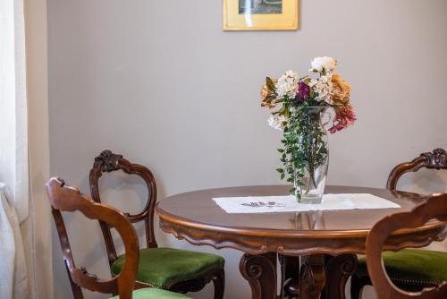 a vase of flowers on a table with two chairs at L'arco del pellegrino in Monteroni dʼArbia