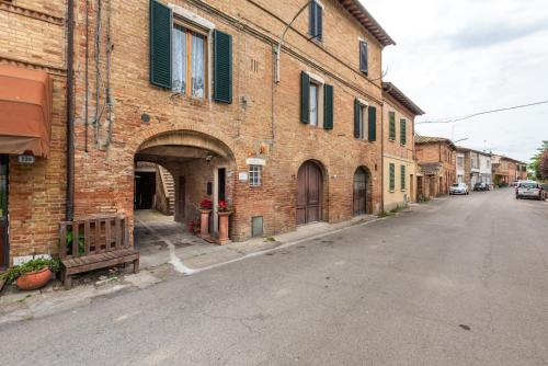 an empty street next to a brick building at L'arco del pellegrino in Monteroni dʼArbia