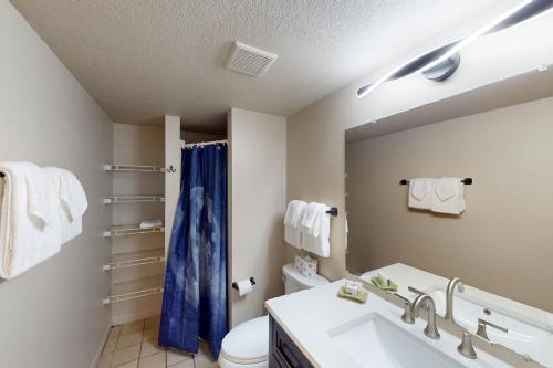 a bathroom with a sink and a blue shower curtain at Fiesta Sol Condominiums 212 in South Padre Island