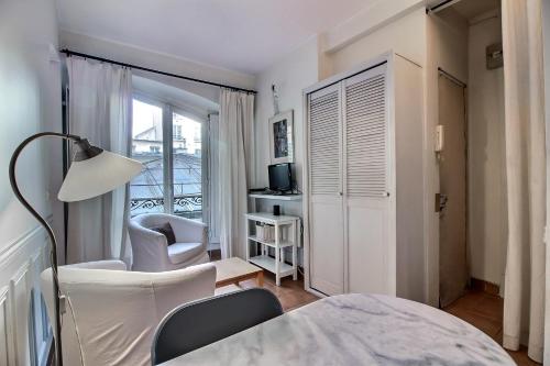 Cette chambre blanche dispose d'un lit, d'une chaise et d'une fenêtre. dans l'établissement Parisian Home I S04308 I Marais, à Paris