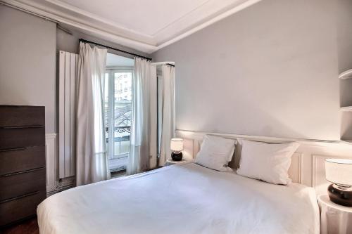 une chambre blanche avec un grand lit et une fenêtre dans l'établissement Parisian Home I S04308 I Marais, à Paris