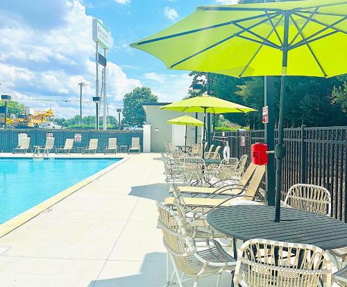 a table and chairs with yellow umbrellas next to a pool at Wyndham Garden Greensboro in Greensboro