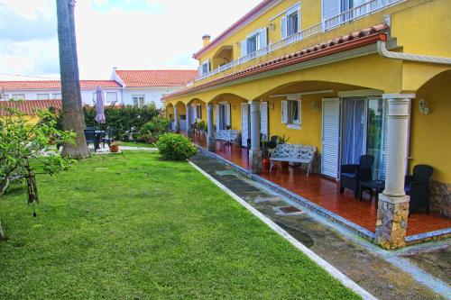 a yellow house with a green yard next to it at Casa das Palmas in Óbidos