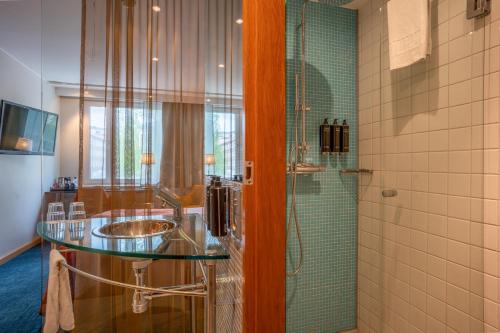 a bathroom with a glass sink and a shower at ProfilHotels Aveny in Umeå