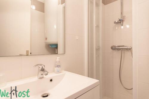 une salle de bain avec un lavabo et une douche avec un miroir dans l'établissement Bouchardat - near sea - 2p, à La Baule