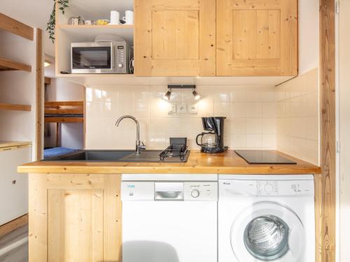 a small kitchen with a washer and dryer at Très bel appartement exposition sud classé 3 étoiles in Chamrousse