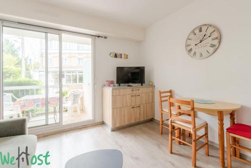 - un salon avec une table et une horloge murale dans l'établissement Bouchardat - near sea - 2p, à La Baule