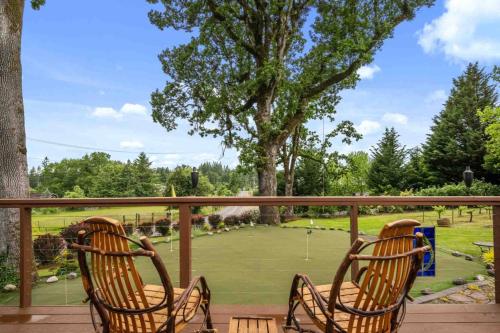 two chairs sitting on a deck with a tennis court at Hoffman Woods Estate in West Linn
