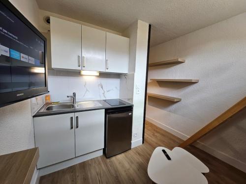 une petite cuisine avec des armoires blanches et un évier dans l'établissement Studio cosy au pied des pistes -centre Praz de Lys, à Taninges