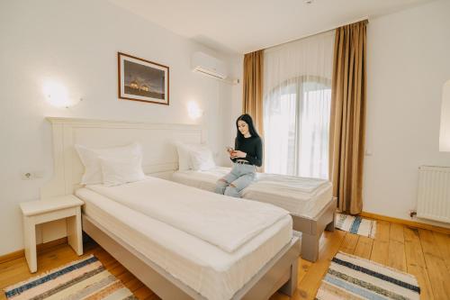 a woman sitting on two beds in a hotel room at Veranda Panzio in Remetea