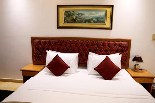 a bedroom with a large white bed with red pillows at Bayan International Hotel in Mawāliḩ