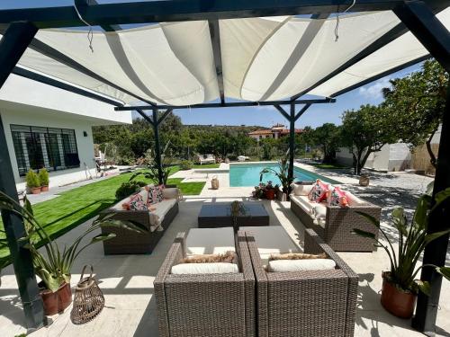 a patio with couches and a large umbrella at GATU Villa Luna Casa de campo con piscina privada in Melegis