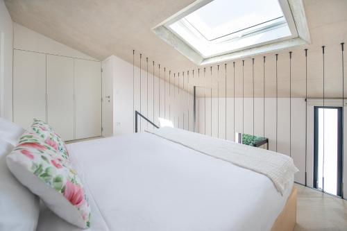 ein Schlafzimmer mit einem weißen Bett und einem Dachfenster in der Unterkunft T0 do Carril, Aveiro in Aveiro