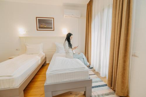 a woman sitting in a hotel room looking out the window at Veranda Panzio in Remetea