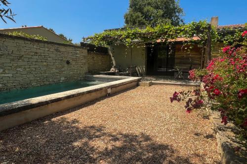 un patio trasero con piscina y algunas flores en Gîte tout confort - jardin et piscine chauffée, en Lagnes