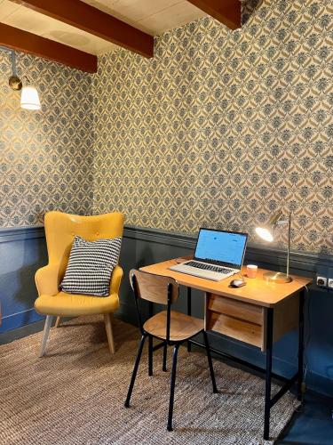 - un bureau avec un ordinateur portable placé à côté d'une chaise dans l'établissement La Stuga, Gîte cocooning au cœur des volcans, à Ludesse