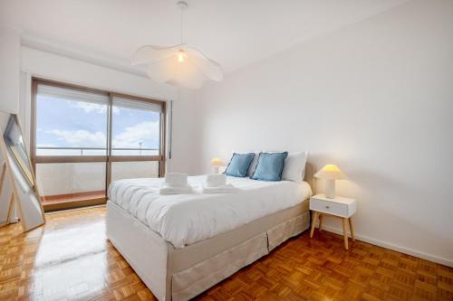 Un dormitorio blanco con una cama grande y una ventana. en Beach Front Apartment Av dos Banhos, en Póvoa de Varzim