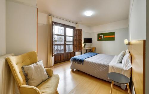 a bedroom with a bed and a chair and a window at Mayor 71- El Hostalito in El Burgo de Osma