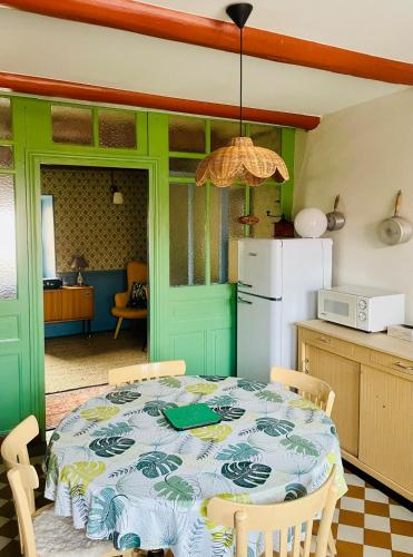 une cuisine avec une table et un réfrigérateur blanc dans l'établissement La Stuga, Gîte cocooning au cœur des volcans, à Ludesse