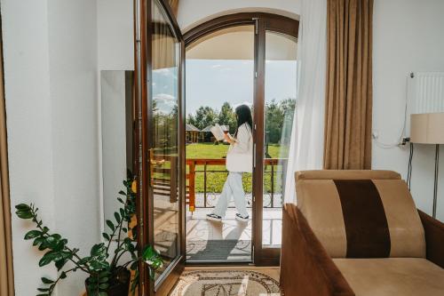 a woman standing on a balcony looking out the door at Veranda Panzio in Remetea