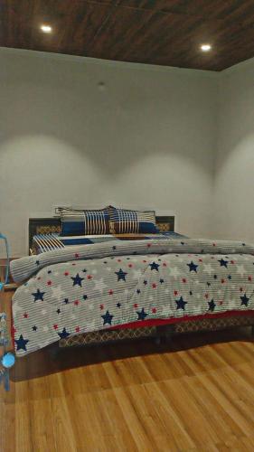 a bed with a comforter with stars on it at River side cafe guest cottage in Shamshi
