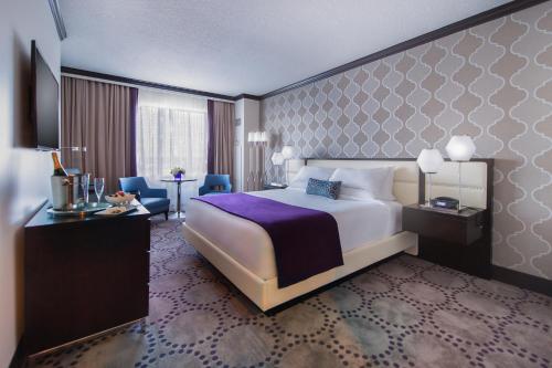 a hotel room with a large bed and a desk at Harrah's Gulf Coast, A Caesars Destination in Biloxi
