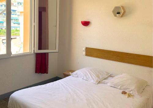 a bedroom with a white bed with a red heart on the wall at Hôtel Le Carnon in Carnon-Plage