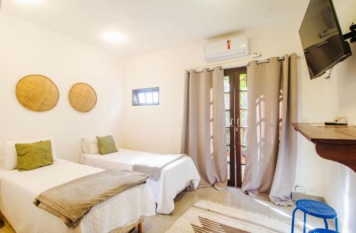 a white room with two beds and a tv at Pousada Sambaki in Paraty