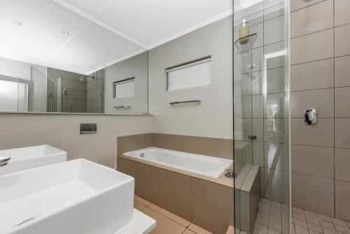 a bathroom with a tub and a sink and a shower at The Odyssey Lifestyle Complex Morningside - 2 BR in Johannesburg