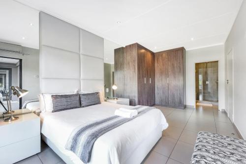 a white bedroom with a large bed and a desk at The Odyssey Lifestyle Complex Morningside - 2 BR in Johannesburg