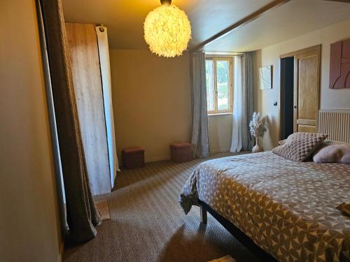 une chambre avec un lit et un lustre dans l'établissement La ferme de Cruz chez Lisa, à Cruzilles-lès-Mépillat