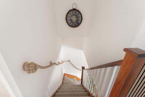 a stairway with a clock on the wall at Drift & Dune in Poole