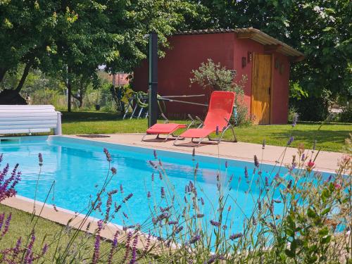 - deux chaises rouges installées à côté de la piscine dans l'établissement La ferme de Cruz chez Lisa, à Cruzilles-lès-Mépillat